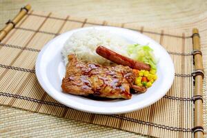 Japanese style sauteed chicken with, sausage, rice and vegetables served in plate isolated on table side view of Hong Kong food photo