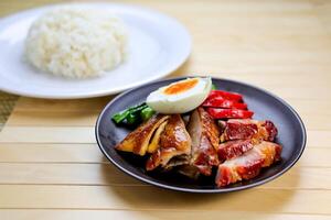 Roast Duck and Char Siu with Rice and salted boiled egg served in plate isolated on table closeup side view of Hong Kong food photo