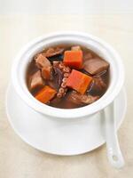 Lotus root, squid, conch and pork tendon soup or Octopus and Carrot Soup served in broth isolated on background side view of Hong Kong food photo