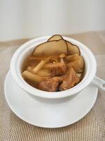 Pork tendon soup with sea coconut, ophiopogon japonicus and Sichuan fritillaria served in broth isolated on background side view of Hong Kong food photo