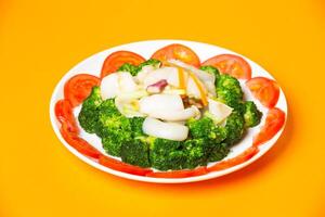Fried Squid with Broccoli served in plate isolated on orange background side view of hong kong food photo