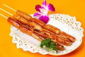 Grilled Chicken Cheese Sausage on Skewers served in plate isolated on orange background side view of hong kong food photo