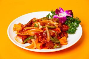 Sweet and Sour Pork with Pineapple, bell peppers, and onions served in plate isolated on orange background side view of hong kong food photo