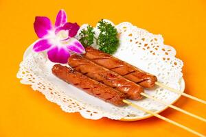 Grilled Chicken Sausage on Skewers served in plate isolated on orange background side view of hong kong food photo