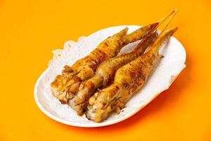 Grilled Chicken Wings on Skewers served in plate isolated on orange background side view of hong kong food photo