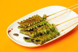Grilled Green Beans Skewers sticks served in plate isolated on orange background side view of hong kong food photo