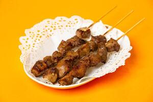 Roasted Beef Tongue skewers served in plate isolated on orange background side view of hong kong food photo