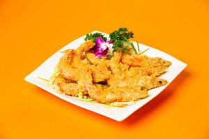 Crispy Golden Salted Egg Prawns served in plate isolated on orange background side view of hong kong food photo