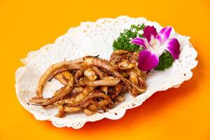 Grilled Squid Tentacles served in plate isolated on orange background side view of hong kong food photo