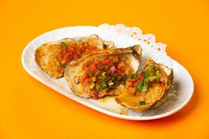 Grilled Hiroshima Oysters with Garlic Sauce served in plate isolated on orange background side view of hong kong food photo