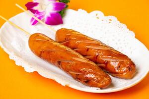 Grilled Scallop Sausage on Skewers served in plate isolated on orange background side view of hong kong food photo