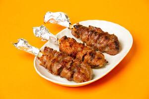 Grilled Piglet spleen skewers or Foil Handles served in basket isolated on orange background side view of hong kong food photo