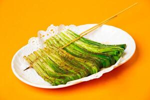 Grilled Scallion Skewers served in plate isolated on orange background side view of hong kong food photo