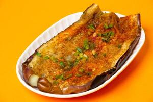 Grilled Japanese Eggplant with garlic and chopped scallions served in plate isolated on orange background side view of hong kong food photo