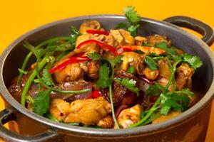 Chinese Spicy Chicken Pot topped with coriander served in pot isolated on orange background side view of hong kong food photo