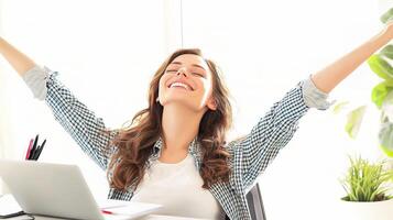 A woman is sitting at her desk with her arms up photo