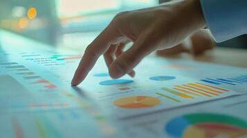 A business person's hand is pointing at a chart photo