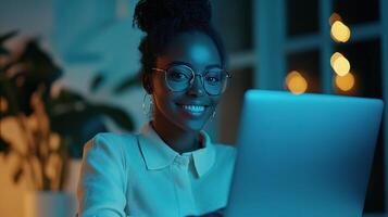 un mujer en lentes es sonriente mientras utilizando un ordenador portátil foto
