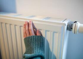 Woman warms up hands over heater. Concept of the need for good central heating. photo
