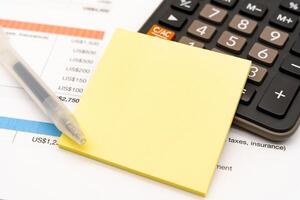 Blank Yellow Sticky note with calculator background. Financial data analyzing. Working on desk with using calculator, finance accounting. Copy space. photo