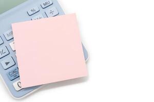 Blank Pink Sticky note with calculator background. Financial data analyzing. Copy space for text on sticky note. isolated on white background. photo