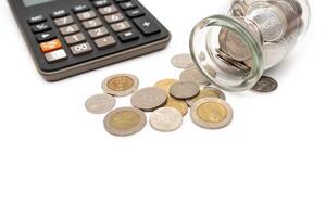 Thai Baht Coins spilled out of jar glass and Calculator isolated on white background, saving for future, Investment business concept. Business and Financial Concept. Copy space. photo