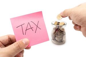 Saving money concept with TAX text on pink sticky note. placing a coin into a jar. isolated on white background. photo
