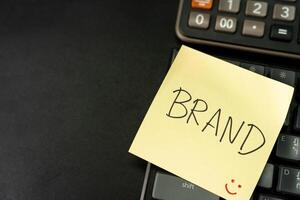 BRAND text with yellow sticky note on keyboard. Build your Brand. Brand building, success, business. Copy Space. photo