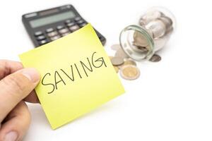 SAVING text with sticky note, calculator and Coins in glass money jar isolated on white background, financial concept. photo