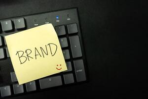 BRAND text with sticky note on keyboard. Build your Brand. Brand building, success, business. Copy Space. photo