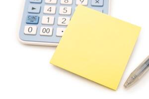 Blank Yellow Sticky note with calculator background. Financial data analyzing. Copy space for text on sticky note. isolated on white background. photo