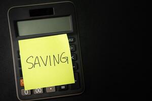 SAVING text with sticky note on calculator. financial concept. Saving money concept. Retirement concept. Pension calculation concept. Copy space. photo