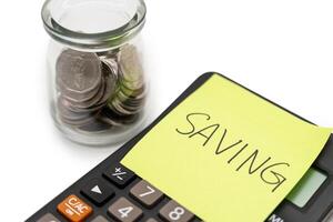 SAVING text with sticky note on calculator and Coins in glass money jar isolated on white background, financial concept. photo