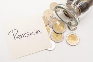 Pension Text on paper note with Thai Baht Coins spilled out of jar glass background, saving for future. photo