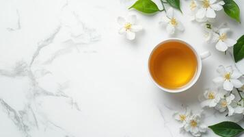 Tea cup with jasmine flowers on white marble background top view photo