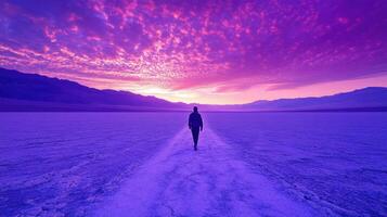 A man walking in the desert with a purple sky photo