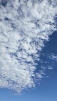 Bright and serene blue sky scattered with fluffy white clouds, depicting the beauty of tranquility. Perfect background for concepts such as freedom, nature, photo