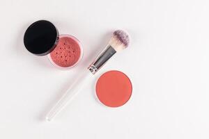 chic makeup brushes and two blush in an open jar, a pink tone block on a white embossed background. top view. A copy space. The concept of beauty. photo