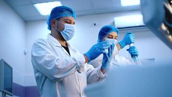 Side view of two scientists use lab equipment for an experiment, working with test tubes and samples. Concept of scientific research and experiments using cutting-edge technology video