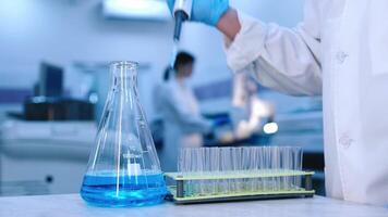 Close-up of test tubes with blue liquid and pipette pouring substance in modern laboratory with advanced equipment. The concept of research and experiments video