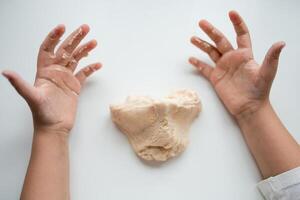 Child hands playing with soft dough on white background photo