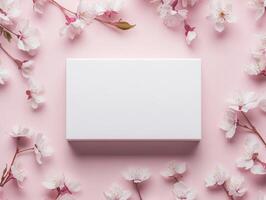 Minimalist mockup of a blank white product box with cherry blossom flowers on pink background for elegant packaging design photo