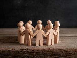 Wooden figures holding hands in a circle, symbolizing unity and community support. photo