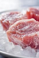 Three pieces of raw meat on ice with a knife photo