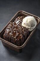 A brownie in a plastic container with ice cream photo