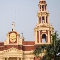 A large church with a clock tower and palm trees photo