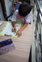 A young boy is drawing on a piece of paper photo