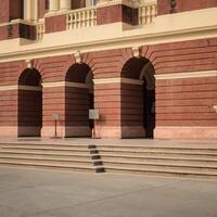A man is sitting on a bench in front of a building photo