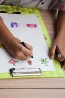 A child drawing on a piece of paper with a pen photo