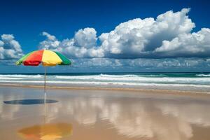A rainbow beach umbrella stands tall on a sandy beach overlooking a calm ocean with a mountain range in the background., photo